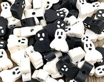 May include: A pile of black and white ghost-shaped beads. The beads have a hole in the centre and are perfect for crafting.