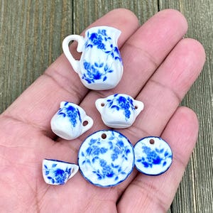 May include: A miniature tea set with a blue and white floral design. The set includes a teapot, two cups, two saucers, and a creamer.