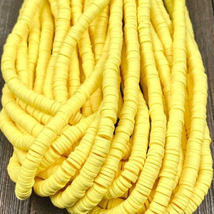 May include: A close-up of a pile of bright yellow round polymer clay beads. The beads are stacked on top of each other, creating a textured and colorful pattern.