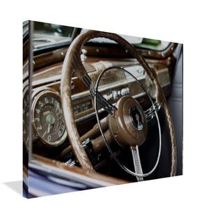 May include: Close-up of a vintage car's interior, showcasing a brown wooden steering wheel with a chrome horn ring. The dashboard features a speedometer and other gauges, all set against a backdrop of rich wood paneling.