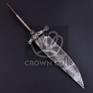 May include: A large, ornate metal blade with a floral pattern etched into the surface. The blade has a long, pointed tip and a wide, curved edge. The handle is a long, threaded rod. The blade is approximately 18 inches long.