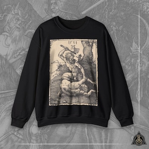 Op de afbeelding: Zwart sweatshirt met een vintage houtsnede van twee figuren, een met een bijl, in een boslandschap. De print bevat de tekst "1511 AD".