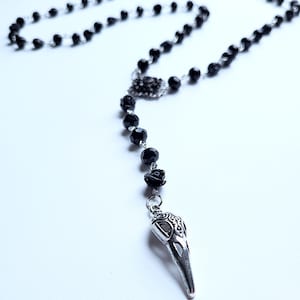 May include: Black beaded rosary necklace with a silver skull pendant and black rose accents.