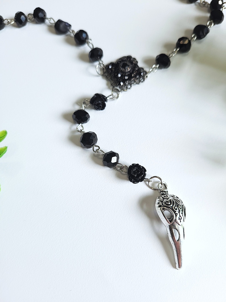 May include: Black beaded necklace with a silver skull pendant and black rose accents.