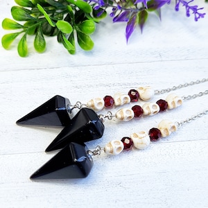May include: Three black crystal pendulum charms with silver chains and white skull beads with red glass beads.