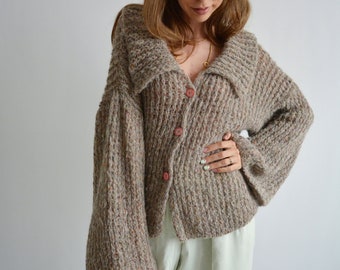May include: A brown speckled knit cardigan with a wide collar and long sleeves. The cardigan has a button closure and a relaxed fit.