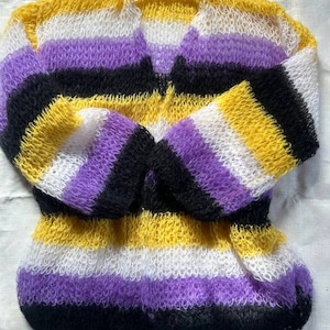 Könnte beinhalten: Ein gestrickter Pullover mit gelben, weißen, violetten und schwarzen Streifen. Der Pullover ist aus weichem, flauschigem Garn gefertigt und hat eine lockere, offene Maschenstruktur.