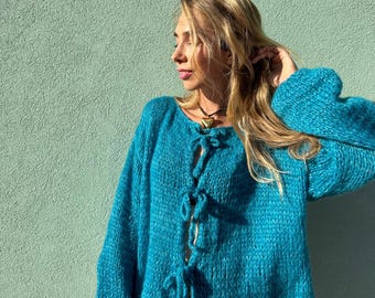 Cárdigan azul de lana merino con cierre de lazo, de largo cropped, ideal para otoño.
