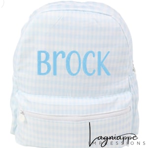 May include: Light blue and white gingham backpack with the name "BROCK" in light blue lettering. The backpack has a front zippered pocket and white zipper pulls. The bag is designed for children.