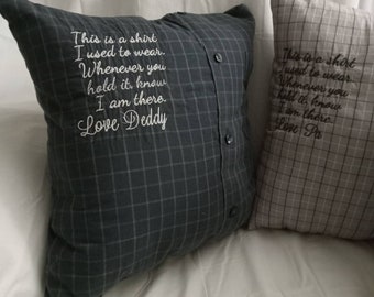 May include: Two pillow covers made from repurposed shirts with embroidered messages. The dark blue pillow cover reads "This is a shirt I used to wear. Whenever you hold it, know I am there. Love Daddy". The light brown pillow cover reads "This is a shirt I used to wear. Whenever you hold it, know I am there. Love Pa".