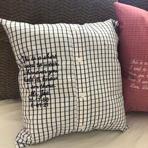 May include: A white and blue plaid pillow with a button closure and embroidered text that reads "This is a shirt used to wear. Whenever you hold it, know I am there. Mr. Joe 10-17-50 6-01-21"