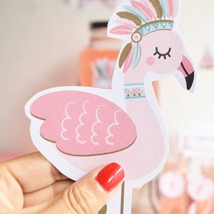 May include: Pink flamingo party decoration with a brown and blue feathered headdress. The flamingo has a pink body with white feathers and a gold beak. The headdress has a white band with a geometric pattern.