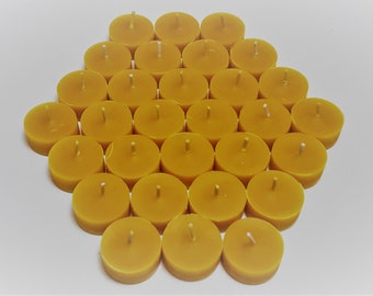 May include: A group of 36 yellow tea light candles arranged in a hexagonal pattern on a white surface.