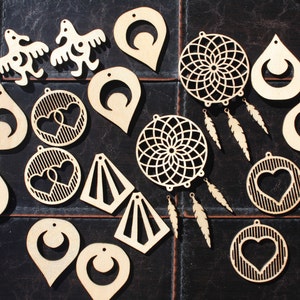 Op de afbeelding: Een verzameling onafgewerkte houten oorbelcomponenten in verschillende vormen. Ontwerpen omvatten druppels, halve manen, harten, geometrische vormen en dromenvangers met veervormige hangers. De stukken zijn lichtbruin en klaar voor personalisatie.