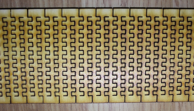 Puede incluir: Primer plano de un rompecabezas de madera con un patr&oacute;n repetitivo de cuadrados entrelazados. El rompecabezas est&aacute; hecho de m&uacute;ltiples piezas que encajan para crear un dise&ntilde;o m&aacute;s grande.