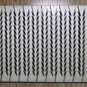 Puede incluir: Una superficie rectangular blanca con un patr&oacute;n repetitivo de formas de chevron negras.