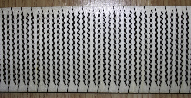 Puede incluir: Una superficie rectangular blanca con un patr&oacute;n repetitivo de formas de chevron negras.