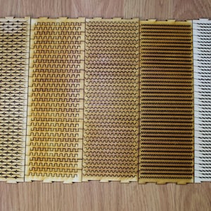 Puede incluir: Siete tiras de madera con diferentes patrones cortados con l&aacute;ser. Los patrones incluyen l&iacute;neas onduladas, zigzags y formas geom&eacute;tricas. Las tiras est&aacute;n dispuestas horizontalmente y todas son del mismo tama&ntilde;o.