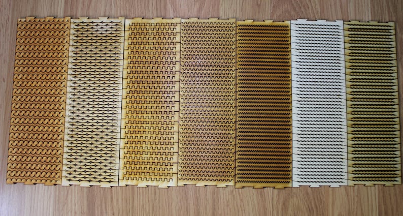 Puede incluir: Siete tiras de madera con diferentes patrones cortados con l&aacute;ser. Los patrones incluyen l&iacute;neas onduladas, zigzags y formas geom&eacute;tricas. Las tiras est&aacute;n dispuestas horizontalmente y todas son del mismo tama&ntilde;o.