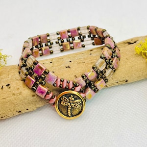 May include: A pink and brown beaded bracelet with a gold dragonfly button closure.