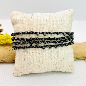 May include: A black beaded bracelet with a multi-strand design. The beads are small and have a speckled finish.