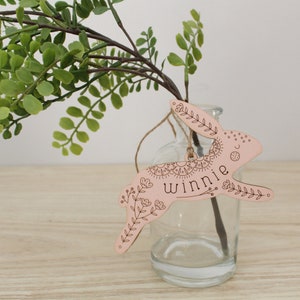 pink wooden easter basket tag shaped like a bunny, personalized with the name winnie. tag is decorated with intricately engraved flowers and whimsical elements. it is shown hanging from a jute string on a glass jar.