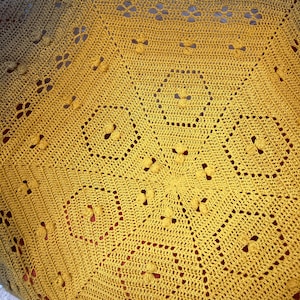 Könnte beinhalten: Nahaufnahme einer gehäkelten Decke mit einem Farbverlaufsmuster in Braun, Gelb und Gold. Die Decke hat ein kreisförmiges Design mit einem Mittelpunkt und strahlenden Linien.