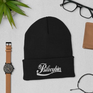 May include: Black beanie with a white embroidered design that says "Psilocybin" in a retro font.