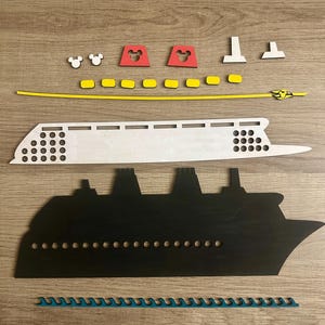 May include: A wooden craft kit to build a cruise ship. The kit includes a white ship hull, a black ship silhouette, yellow and red pieces, and a blue wave piece.