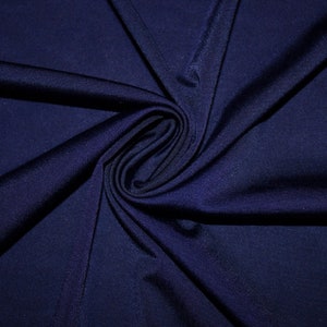 May include: Close-up of a dark blue fabric with a smooth, silky texture. The fabric is folded and draped, creating a soft, flowing look.
