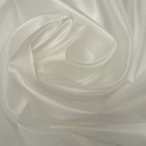May include: White satin fabric with soft, flowing folds. The fabric is smooth and silky to the touch.