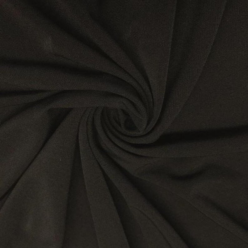 May include: Black ribbed fabric with a soft, smooth texture. The fabric is draped and folded, showing its flexibility and drape.