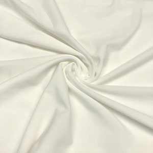 May include: White fabric with a smooth, silky texture. The fabric is draped and folded, creating soft, flowing lines.