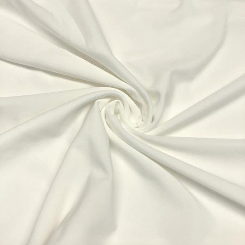 May include: White fabric with a smooth, silky texture. The fabric is draped and folded, creating soft, flowing lines.