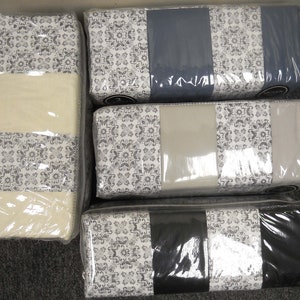 May include: Four sets of packaged bedding with a white and gray patterned design. Each set features a different color accent: blue, gray, beige, and black.