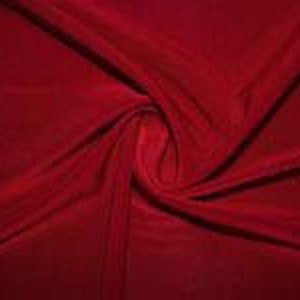 May include: A deep red velvet fabric with a soft, smooth texture. The fabric is draped and twisted, showcasing its luxurious feel.