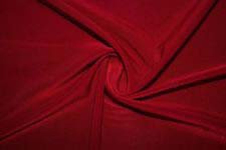 May include: A deep red velvet fabric with a soft, smooth texture. The fabric is draped and twisted, showcasing its luxurious feel.