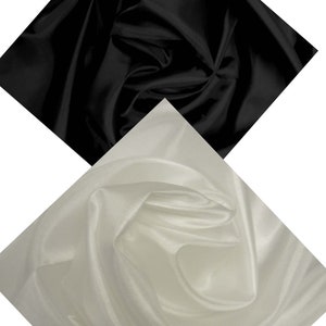 May include: Two pieces of fabric, one black and one white, are draped and folded in a diamond shape. The fabric has a smooth, silky texture.