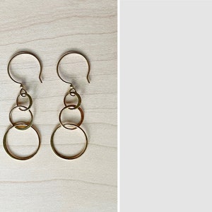 May include: Gold-toned earrings with three interlocking circles hanging from a hook.