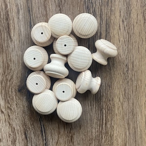 Könnte beinhalten: Eine Sammlung von Holzknöpfen in verschiedenen Formen und Größen, alle mit einer natürlichen Holzoptik. Die Knöpfe sind auf einer Holzoberfläche zu einem Stapel angeordnet.