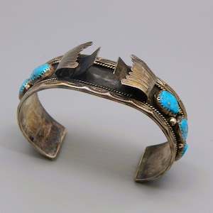 May include: A silver bracelet with turquoise stones and a hinged design. The bracelet is made of sterling silver and features a traditional Native American design.
