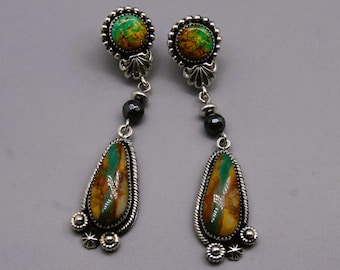May include: A pair of dangle earrings with green, brown, and yellow turquoise stones set in silver. The earrings feature a black bead and three silver beads at the bottom.