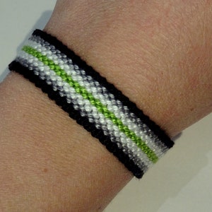 Peut inclure: Un bracelet d'amitié noir, blanc et vert avec un motif tissé.