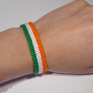 Può includere: Un braccialetto dell'amicizia verde, bianco e arancione. Il braccialetto è intrecciato con tre fili di corda.