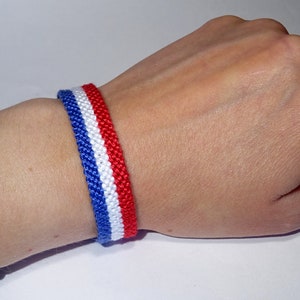 Op de afbeelding: Een rood-wit-blauwe vriendschapsband gemaakt van gevlochten touw.