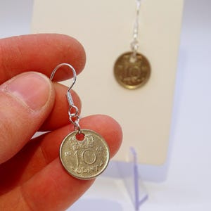 May include: Silver dangle earrings with a 1948 Dutch 10 cent coin charm. The coin features a crown and the text "10 CENT".