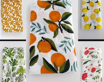May include: Four different baby swaddles with various patterns. The swaddles are made of a soft, breathable fabric. The patterns include lemons, oranges, flowers, and tropical leaves.