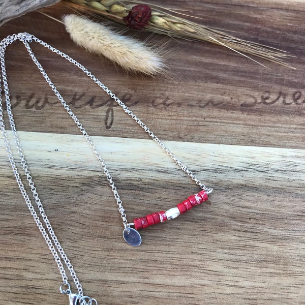 Collier argenté en acier inoxydable et des perles rouges.