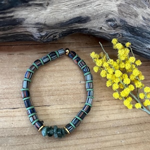 Peut inclure: Un bracelet de perles avec des perles rectangulaires bleues foncées, vertes et rouges. Il comporte des séparateurs verts et des accents dorés. Des pierres vertes et des fleurs jaunes sont également visibles.