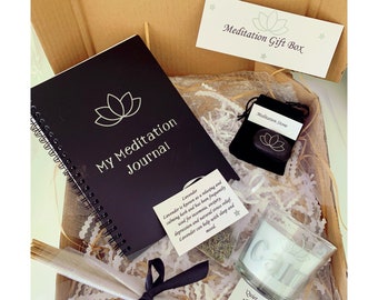 May include: A meditation gift box with a black journal, a meditation stone, incense sticks, a candle, and a small bag of lavender. The journal has a lotus flower design and the text "My Meditation Journal". The candle has the word "Calm" on it. The bag of lavender has the text "Lavender" and information about the benefits of lavender. The meditation stone is in a black velvet bag with the text "Meditation Stone".